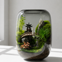 Glass terrarium setup for a Pavilions moss landscape showcasing miniature bridge figurines and decorative stones.