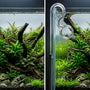 Side-by-side comparison of bulky green plastic aquarium filter tubing versus a nearly invisible clear glass lily pipe in a planted tank.