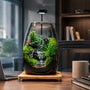 Green Hills moss microlandscape terrarium on a modern wooden office desk next to a laptop as low-maintenance indoor garden decor.
