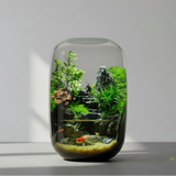 Glass terrarium with plants and rocks on a gray surface